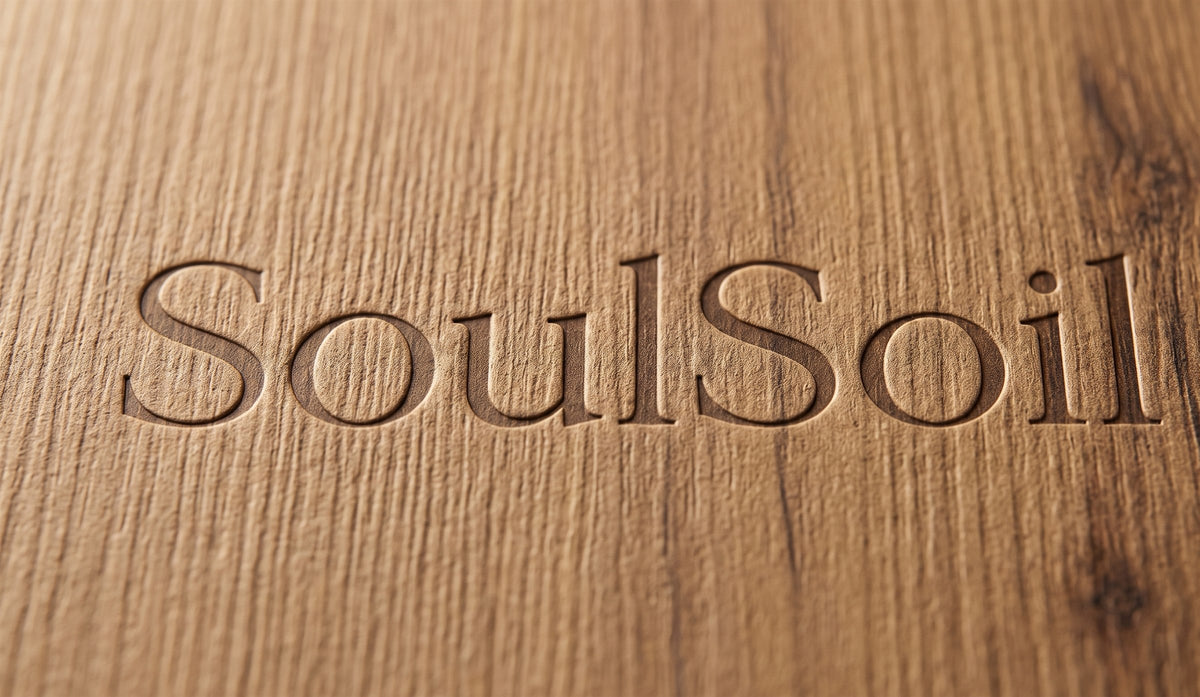 Macro of the SoulSoil wordmark debossed into the wood-grain lid of the box.